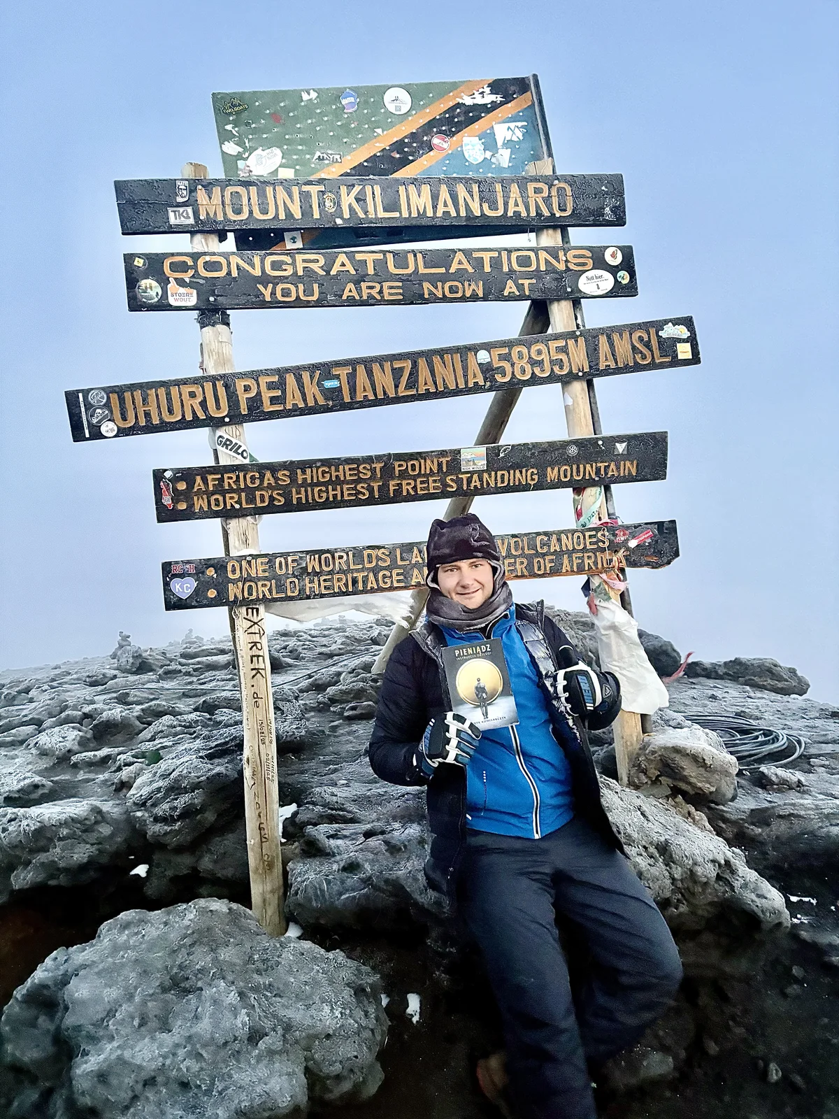 Patryk Komisarczyk z książką na szczycie Uhuru Peak na Kilimandżaro